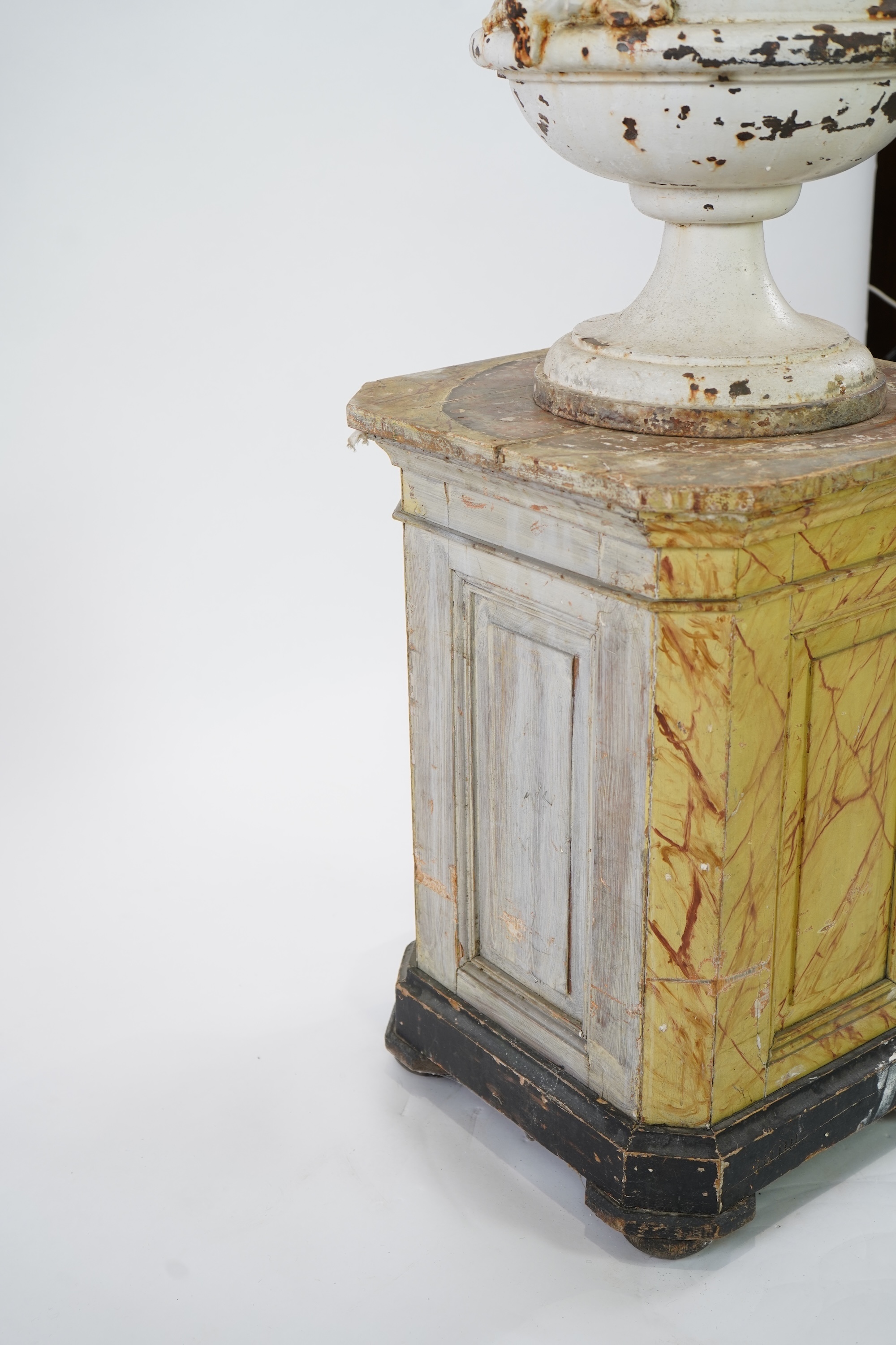 A Victorian white painted cast iron urn and a painted faux marble pedestal